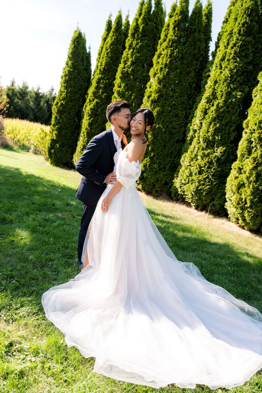 Bride and groom kissing in front of cedars