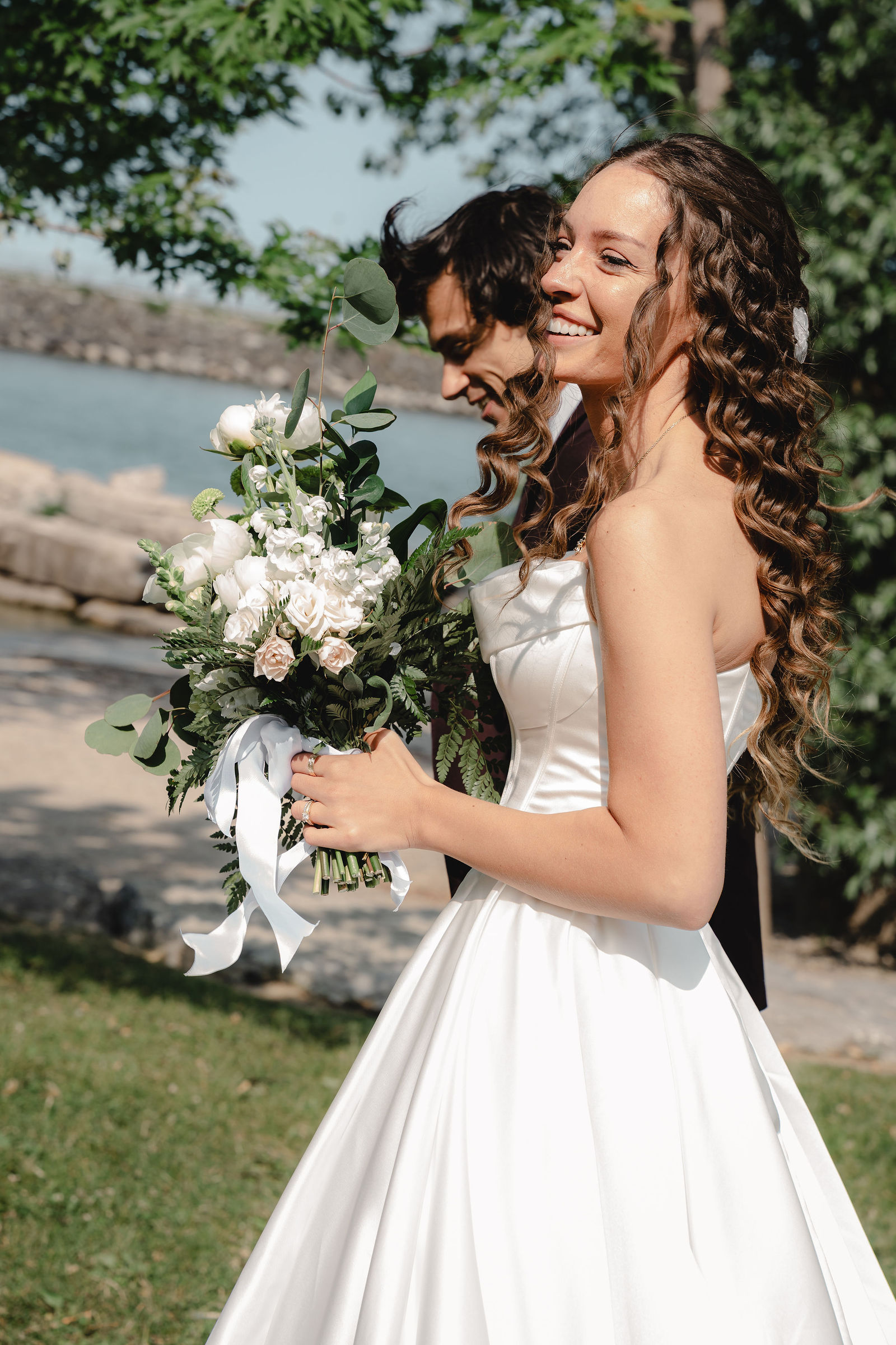 Bride laughing, bouquet by the lake