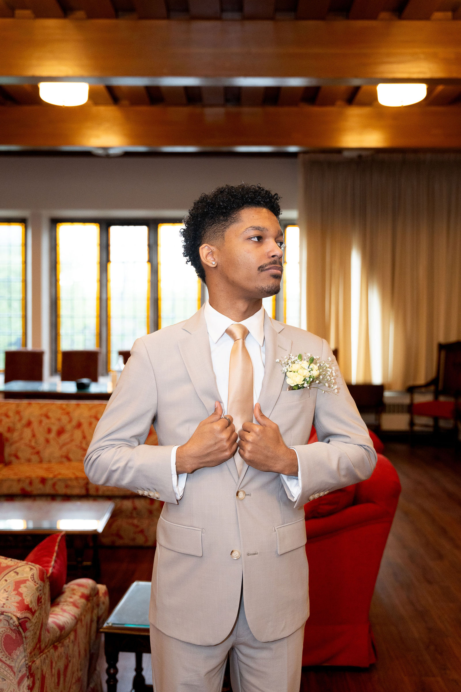 Groom adjusts lapel by windows