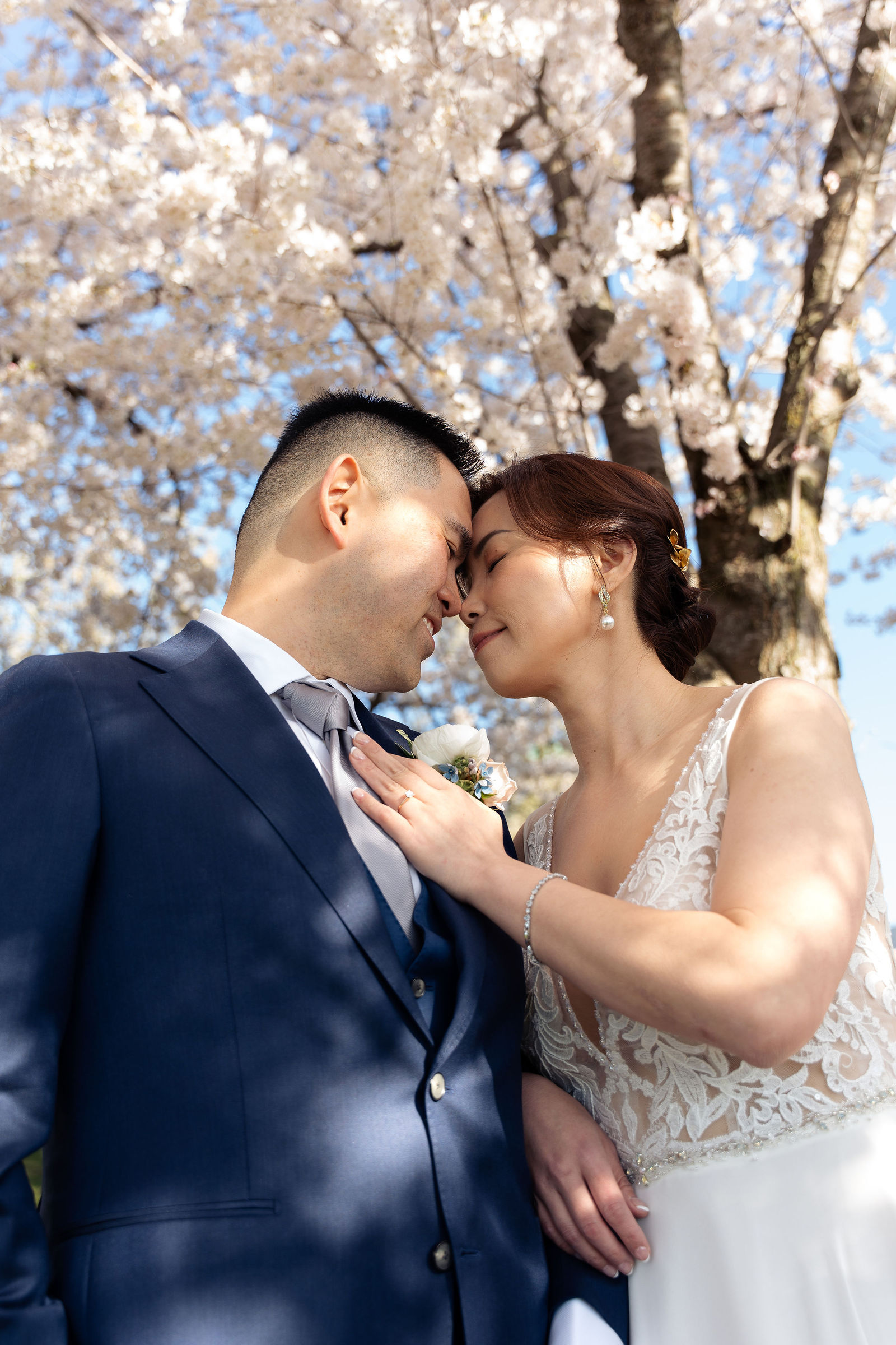 Foreheads together beneath blooming branches