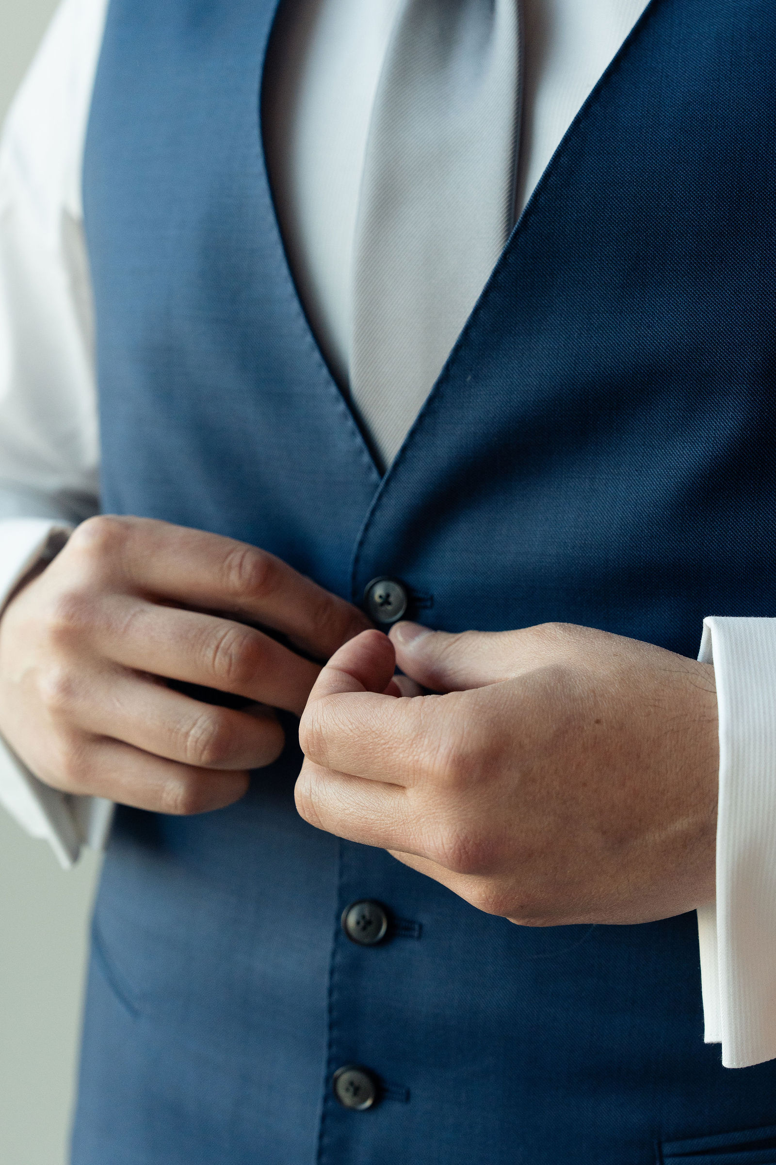 Groom buttons his navy vest