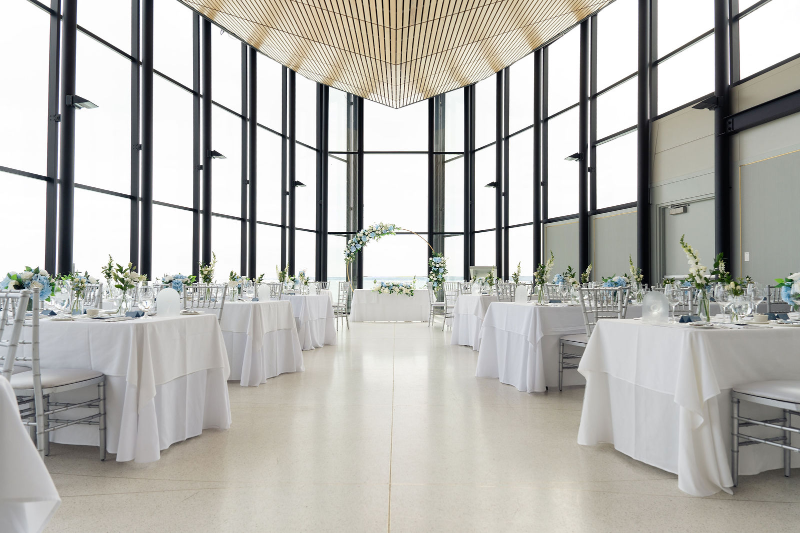 White tables framing floor-to-ceiling lake windows