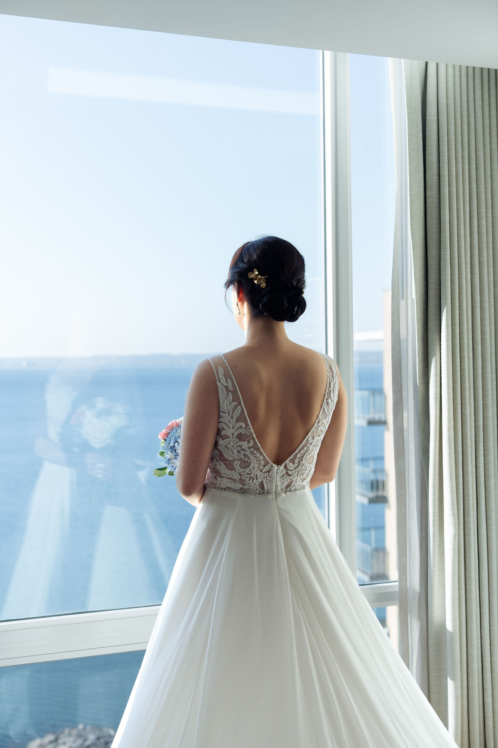 Bride at window above the blue water